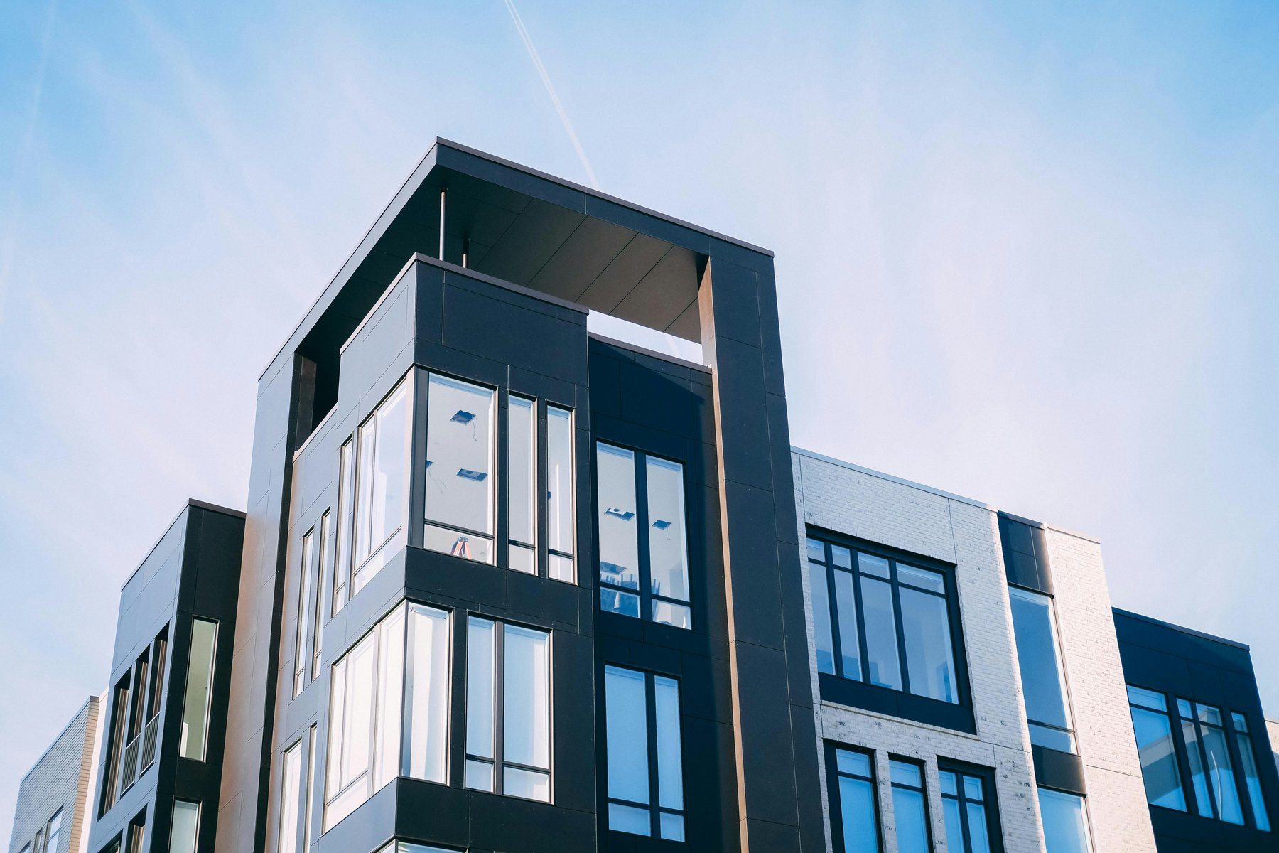 Angular modern apartment building facade in dark and pale cladding panels, low-angle view
