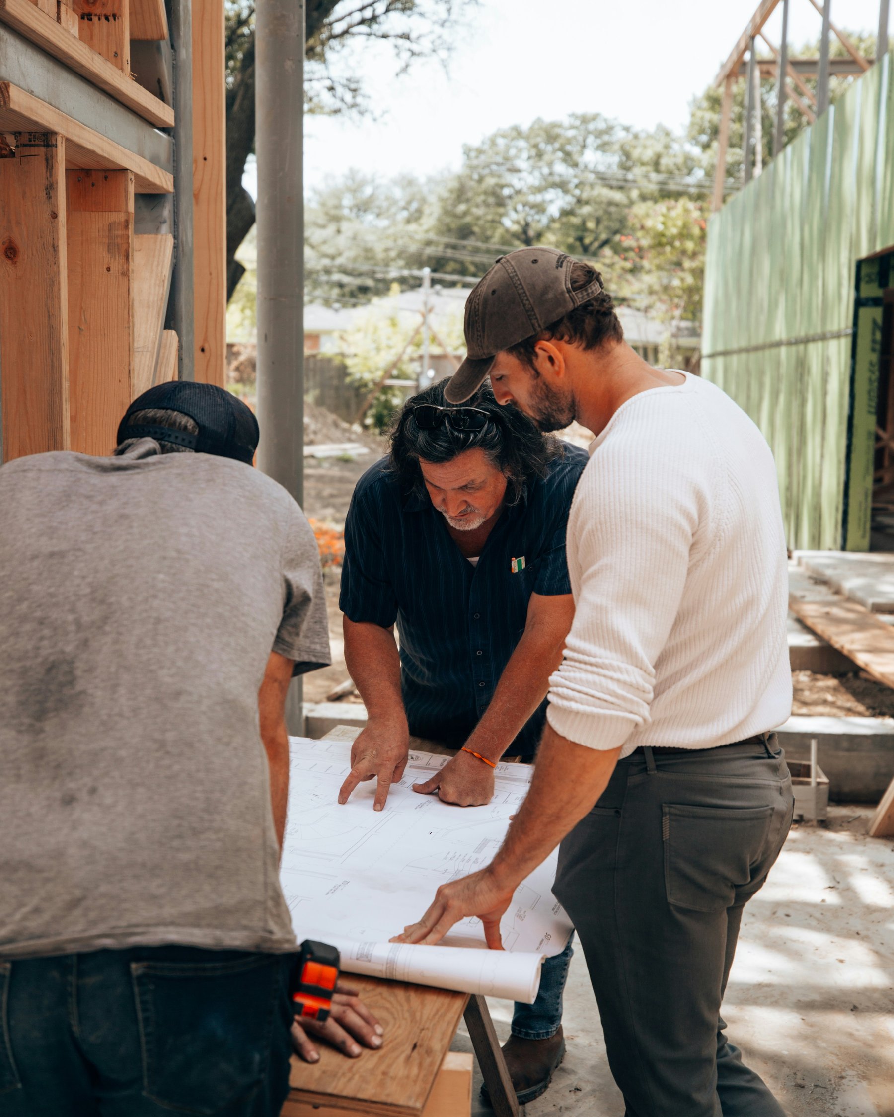 Three people reviewing drawings together on site